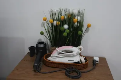 a table with a phone and a vase of flowers at Jo Jo Homestay @ Pangkor Coral Bay Resort in Pasir Bogak