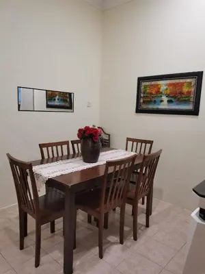a dining room table and chairs with a vase on it at Jalinan Qaseh Homestay in Seri Manjung