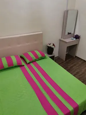 a bedroom with a green and pink bed with a mirror at Jalinan Qaseh Homestay in Seri Manjung