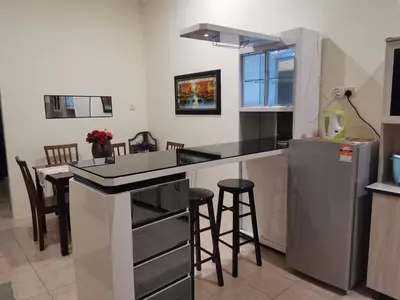 a kitchen with a counter with stools and a refrigerator at Jalinan Qaseh Homestay in Seri Manjung