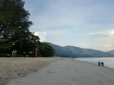 a group of people walking on the beach at By The Sea Deluxe Condo @ Batu Ferringhi Penang in Batu Ferringhi