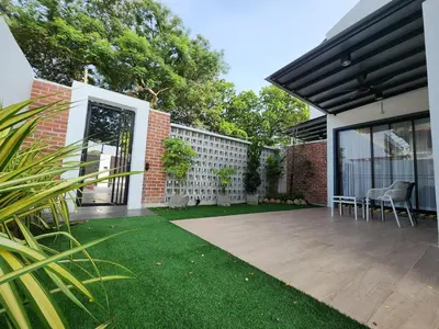 a garden with a patio with chairs and a fence at Ipoh Eden Pool Villa Suites in Ipoh