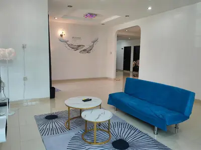 a living room with a blue couch and two tables at Padang Serai Roomstay Family Suite Share Bathroom804 in Padang Serai