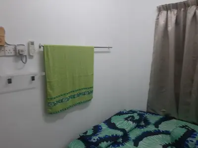 a green towel hanging on a wall next to a window at DIAMOND HOMESTAY in Kuala Kangsar