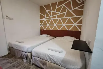two beds in a small room with a wall at Maleeq Hotel Meru Ipoh in Ipoh
