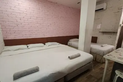 a room with two beds and a brick wall at Maleeq Hotel Meru Ipoh in Ipoh