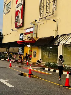 a woman walking down a street with orange cones at Home in Simpang Ampat in Simpang Ampat