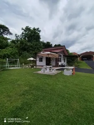 a small white house with an umbrella in a yard at Z&S Gerik Hillview Homestay in Gerik