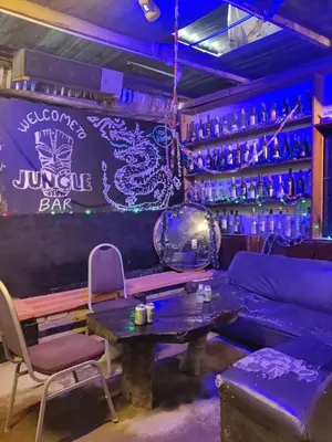 a bar with purple lighting and a couch and a table at Jungle Ippie Hostel in Tanah Rata