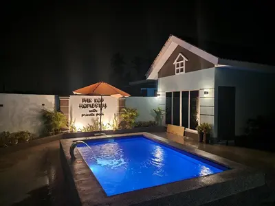 a swimming pool in front of a house at night at ISLAMIC Pak Kop Homestay with private pool in Nibung Tebal