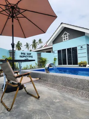 a chair with an umbrella next to a swimming pool at ISLAMIC Pak Kop Homestay with private pool in Nibung Tebal