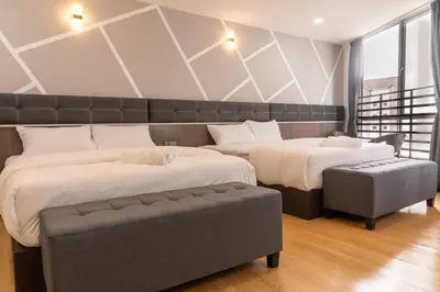 a bedroom with two beds and a bench at Sunrisestay in Brinchang