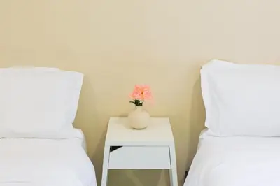 a vase with a flower on a table between two beds at 35 Home4Stay Tanjong Bungalow Wedding BBQ Near Beach restaurant in Tanjung Bungah