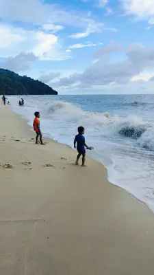 two children playing in the sand on the beach at Nyaman Sweet Home in Balik Pulau