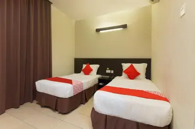 two beds in a hotel room with red pillows at Hotel O Bei King in Sitiawan
