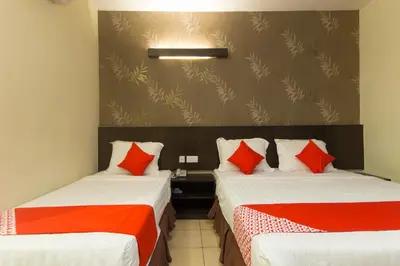 two beds in a room with red and orange pillows at Hotel O Bei King in Sitiawan