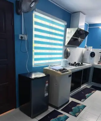 a kitchen with a stove and a blue wall at MyLittle Homestay in Tanjung Malim
