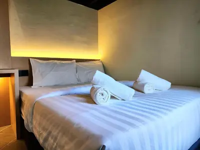 a bed with white sheets and pillows on it at Georgetown AY Hotel in George Town