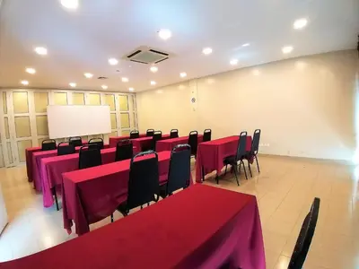 a conference room with red tables and chairs and a white screen at Hotel Jelai @ Raub, Pahang in Raub