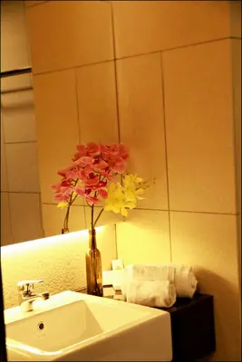 a bathroom with a sink and a vase with flowers at U Hotel Penang in Bayan Lepas