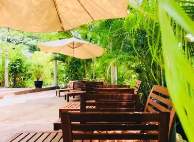 a group of wooden tables and chairs with an umbrella at EFM GREENLAND IPOH in Ipoh
