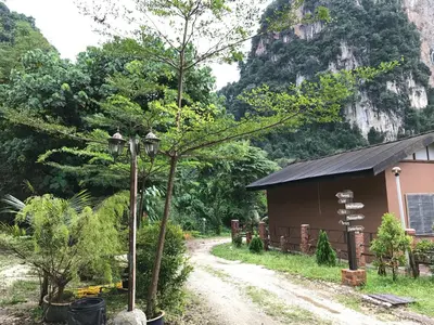 a dirt road next to a building with a mountain in the background at EFM GREENLAND IPOH in Ipoh