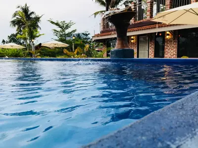 a swimming pool in front of a building with umbrellas at EFM GREENLAND IPOH in Ipoh
