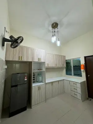 a kitchen with wooden cabinets and a black refrigerator at Ruzarani Home Meru Suria in Chemor