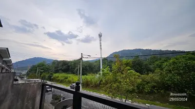 a person sitting on a balcony looking at a mountain at Ruzarani Home Meru Suria in Chemor