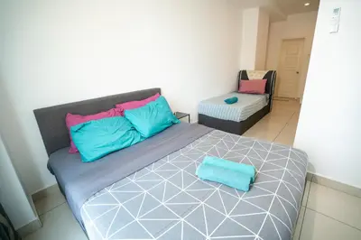 a bed with blue and pink pillows and a chair at Seaview mansion one Georgetown Penang in George Town