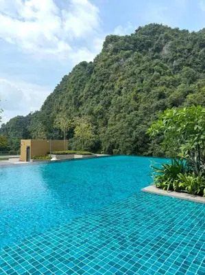 a large blue swimming pool with a mountain in the background at Lost World Tambun 1BR 3/4Pax @Sunway Onsen Suite in Kampong Batu Lapan