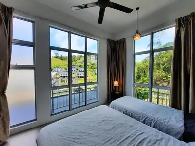 a bedroom with large windows and a bed with white sheets at 1BR Cool Homestay at Cameron Golden Hills Night Market in Brinchang