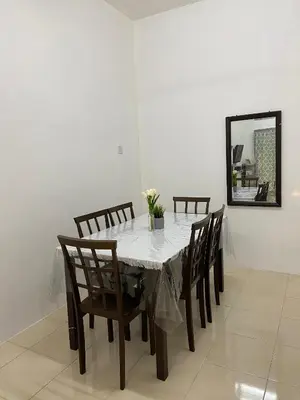 a dining room table with chairs and a mirror at EmyNuar Homestay in Batu Kurau