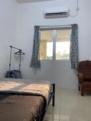 a bedroom with a bed and a window with curtains at EmyNuar Homestay in Batu Kurau