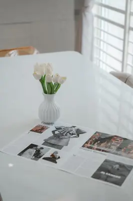 a vase of flowers on a table with a newspaper at BrandNew Premium House 4Room12Pax@ALMA NEAR JUSCO in Bukit Mertajam