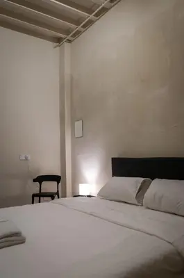 a white bedroom with a bed and a chair at Aayu Beach St - George Town Penang in George Town