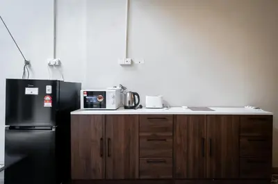 a kitchen with a black refrigerator and wooden cabinets at Aayu Beach St - George Town Penang in George Town