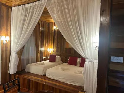 a bedroom with two beds with white curtains at Woodcookies Guesthouse in Pangkor