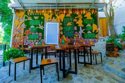 a restaurant with tables and chairs in front of a wall at Woodcookies Guesthouse in Pangkor