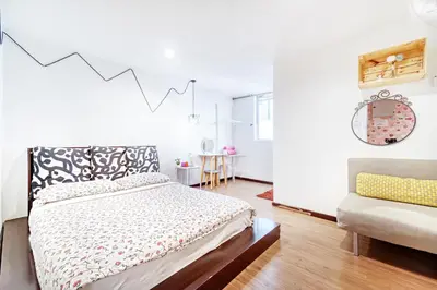 a white bedroom with a bed and a chair at Snooze Hotel in Brinchang