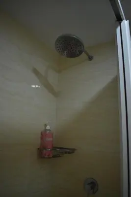 a bathroom with a shower with a bottle on a shelf at Seaview - Sri Sayang in Batu Ferringhi