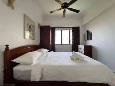 a bedroom with a white bed with a ceiling fan at Seaview - Sri Sayang in Batu Ferringhi