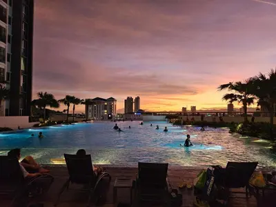 a group of people in a swimming pool at sunset at Newly Furnished Metropol Service Apartment with Attractive View in Bukit Mertajam