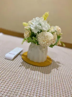 a vase filled with white flowers next to a remote control at Newly Furnished Metropol Service Apartment with Attractive View in Bukit Mertajam