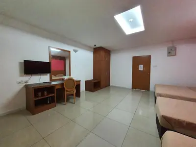 a room with a bedroom with a desk and a television at Cool Point Hotel in Tanah Rata