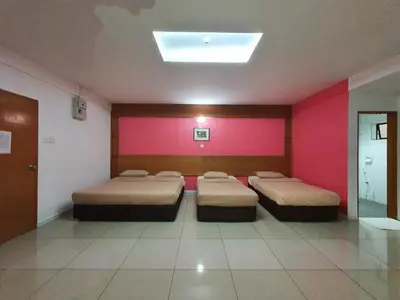 a room with three beds and pink walls at Cool Point Hotel in Tanah Rata