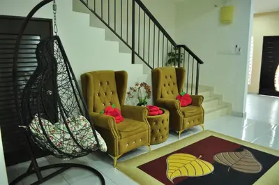 two chairs in a living room with a staircase at Uwais Homestay Segari Lumut in Lumut