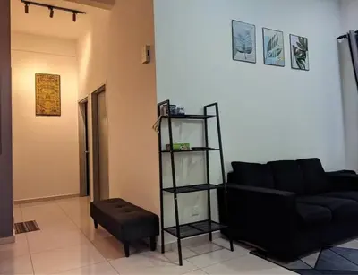 a living room with a black couch and a stool at IZZ Homestay MUSLiiM in Ipoh
