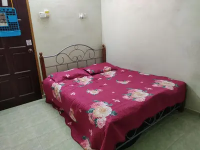 a bed with a pink comforter on it in a room at Penang Green Homestay 1st Floor in Permatang Pauh