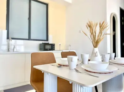 a white dining room table with chairs and a vase at Urban Suites #Creamy style #Infinity Pool #local neighbourhood #5pax #3BR 2bath #2Queen 1Single #Quality well maintained #Private host in Jelutong